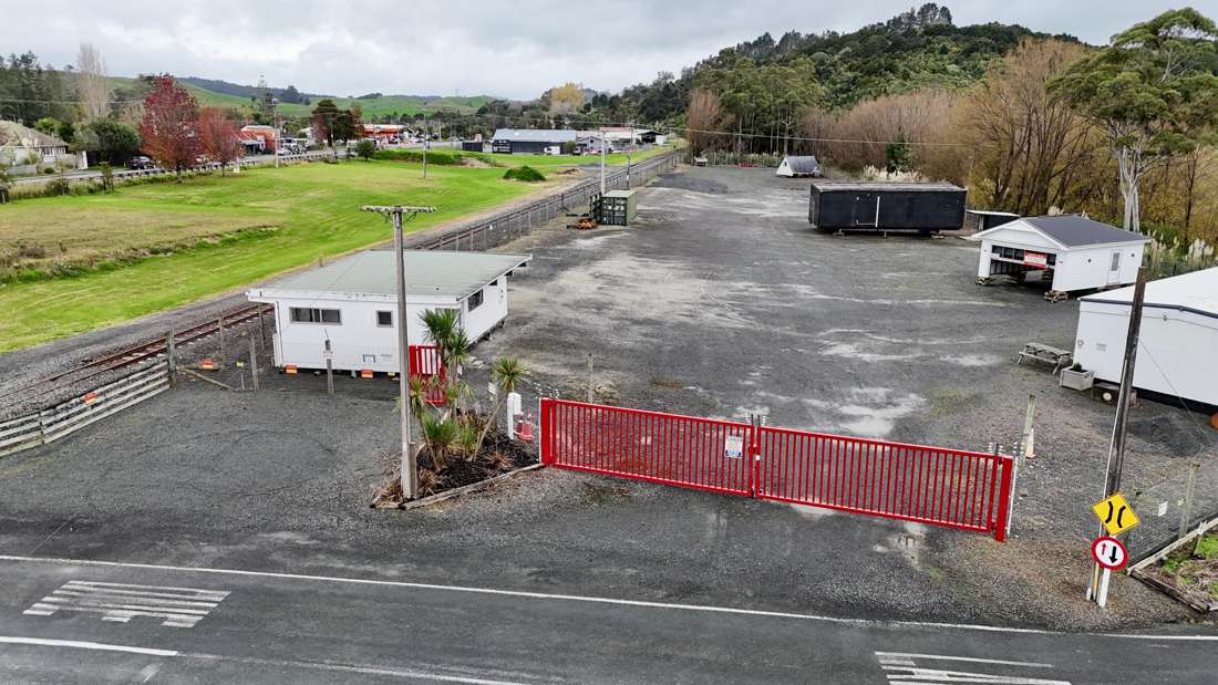 The yard entrance at 3 Silver Hill Road, with red security gates, the site office and stored buildings on the gravel yard behind